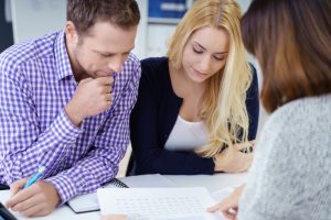 A couple with female broker, looking over charts